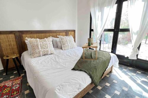 una camera da letto con un grande letto con lenzuola e cuscini bianchi di Villa Sosaryca, piscine Bali a Aït Ghemat