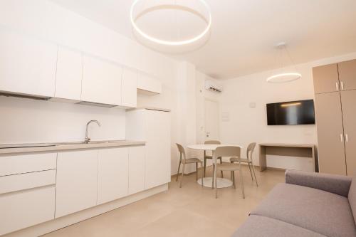 a kitchen with white cabinets and a table with chairs at Agorà Vieste Rooms & Apartments in Vieste