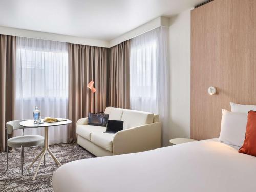 ル・クレムラン・ビセートルにあるノボテル パリ 13 ポルト ディタリーのベッド、ソファ、椅子が備わるホテルルームです。
