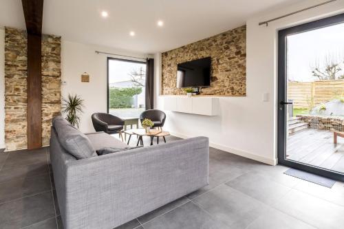 un salon avec un canapé et une télévision dans l'établissement Grand Bretonnerie, à La Haie-Fouassière