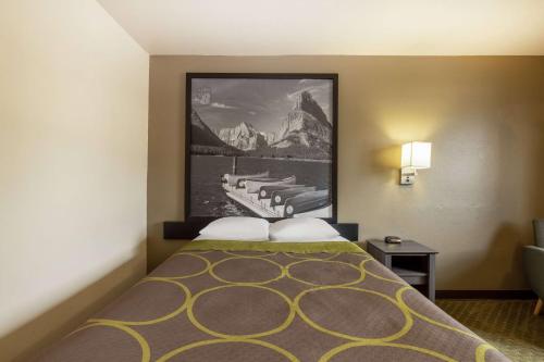 a hotel room with a bed with a picture on the wall at Super 8 by Wyndham Butte MT in Butte
