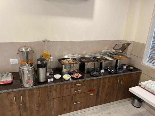 Mayda Residency By Mayda Hospitality Pvt. Ltd. في نيودلهي: مطبخ مع كونتر مع العديد من القدور والمقالي