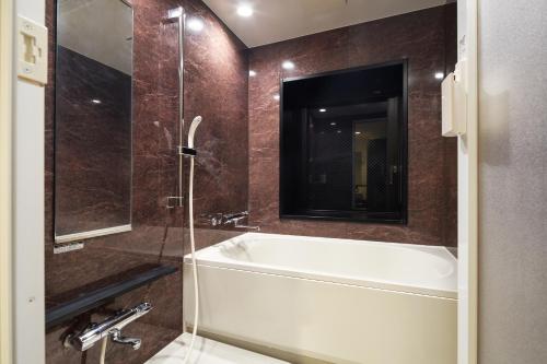 福岡的住宿－Hotel STARRIZE，带浴缸和玻璃淋浴间的浴室。