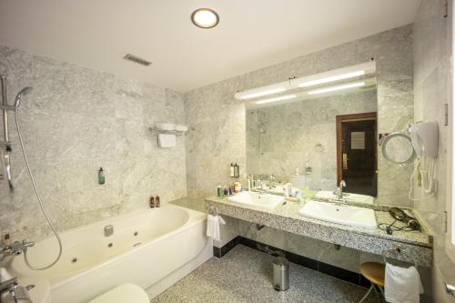 a bathroom with a tub and two sinks and a bath tub at Hotel Florida in San Lorenzo de El Escorial