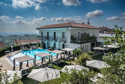 a villa with a swimming pool and tables and umbrellas at Villa Nonna Cicci Boutique Hotel - SPA in Cisterna dʼAsti