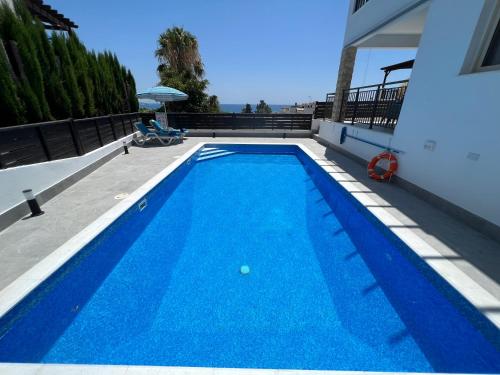 una piscina azul en la parte lateral de un edificio en Villa Marina Sea-View Private Pool en Peyia