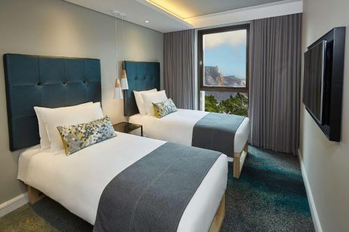 um quarto de hotel com duas camas e uma televisão em StayEasy Cape Town City Bowl em Cidade do Cabo