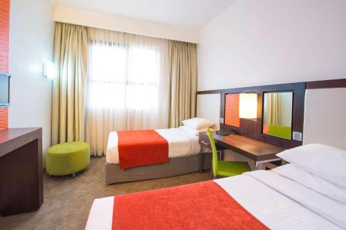 a hotel room with two beds and a desk at StayEasy Lusaka in Lusaka