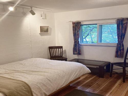 a bedroom with a bed and a chair and a window at Gallery HARA & GUESTHOUSE - Vacation STAY 68646v in Hara