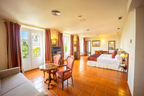 サン・ロレンソ・デ・エル・エスコリアルにあるホテル フロリダのベッド、テーブル、椅子が備わるホテルルームです。