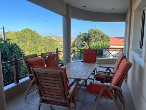 a porch with a wooden table and chairs on a balcony at Ornela's Home in Yiánnidhes