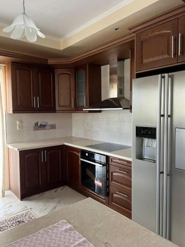 a kitchen with wooden cabinets and stainless steel appliances at Ornela's Home in Yiánnidhes