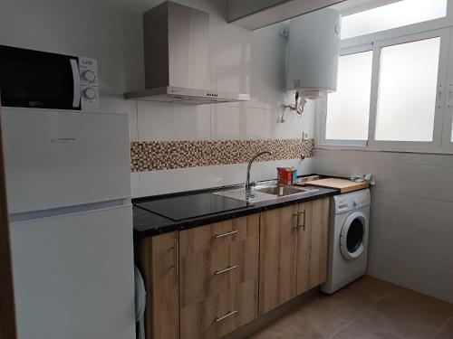 a kitchen with a sink and a washing machine at Delicia, Sol y mar in Málaga