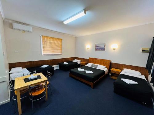 a room with beds and a table and chairs at Horsham Motel in Horsham