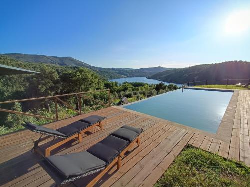 a group of chairs sitting on a deck next to a pool at Casas de Gondarem by the Douro Valley in Raiva