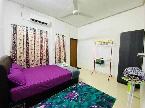 a living room with a purple couch and a rug at Homestay Ummi in Kuala Terengganu