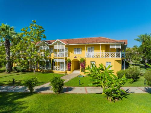 una casa amarilla con patio en Euphoria Palm Beach Resort, en Kizilagac