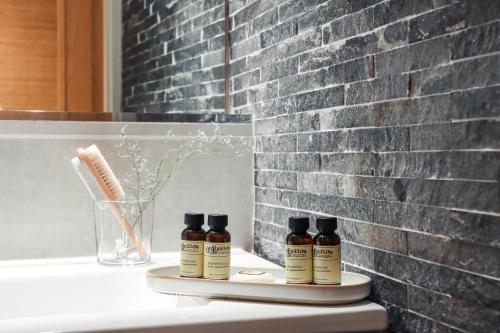 a bathroom with three bottles of essential oils on a counter at Hôtel Le Pré Galoffre in Nîmes