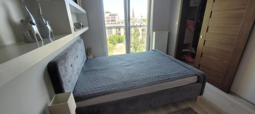 Cama pequeña en habitación con ventana en Apartament Neptun en Olsztyn