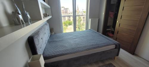 małe łóżko w pokoju z oknem w obiekcie Apartament Neptun w Olsztynie