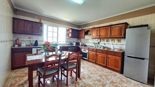 a kitchen with a table and a white refrigerator at Casa Ventura in Arco da Calheta