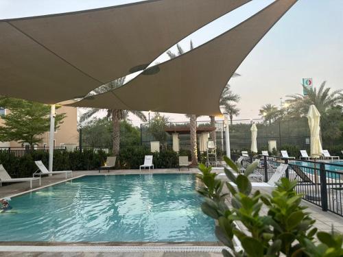 a swimming pool with an umbrella in a resort at Luxurious 3BR Villa Amaranta in Dubai