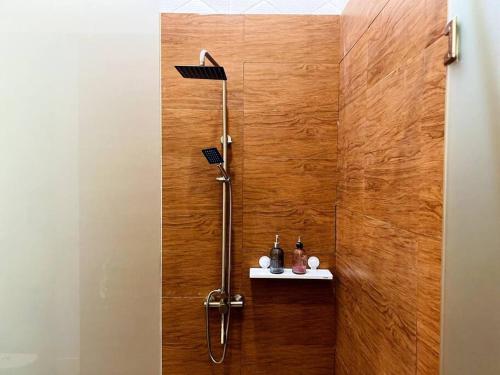 a shower in a bathroom with a wooden wall at Skyline BlueDome Villa Ciwidey in Ciwidey