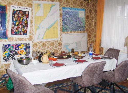einen Tisch mit einer weißen Tischdecke und Stühlen in einem Zimmer in der Unterkunft Brasserie de l'Eichel-t-Ale in Voellerdingen