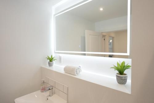 Baño blanco con espejo y lavabo en Cosy 1 bed - Heart of Birmingham, en Birmingham