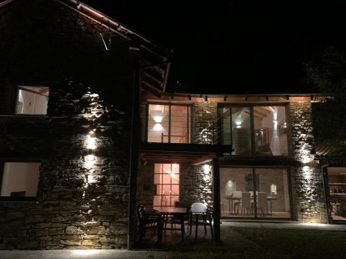 een stenen huis met een tafel buiten 's nachts bij Sous Un Ciel Différent Struttura con sauna privata in Cortemilia