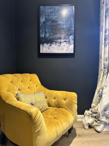 un sofá amarillo sentado en una habitación con una pintura en Unique Clifton apartment on historic crescent, en Bristol