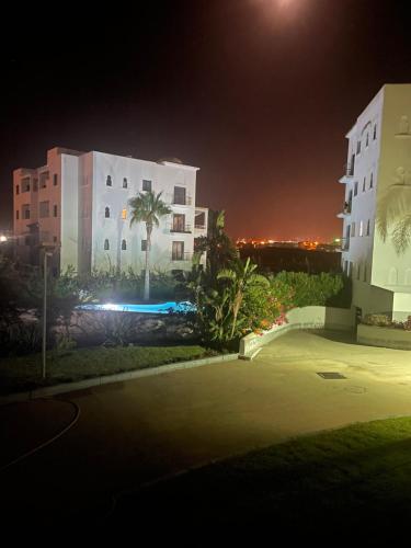 a night view of a building and a parking lot at Charmant appartement dans les jardins d Assilah Piscine et Jardin andalous in Asilah