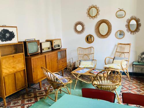 salon z krzesłami, telewizorem i lustrami w obiekcie Les Cagettes en Ville w Perpignanie