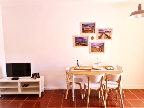 uma sala de jantar com mesa e cadeiras e uma televisão em Abrigo das Matas em Porto Santo