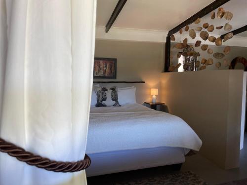 a bedroom with a white bed with a curtain at Howberry Hills in Plettenberg Bay