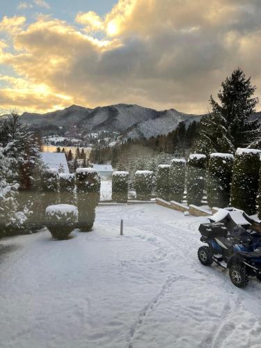 a snow covered yard with a motorcycle parked in the snow at VIP Villa & Spa in Colibiţa