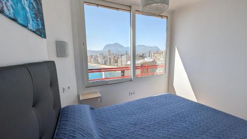 a bedroom with a blue bed and a large window at DON MIGUEL sea view apartment in Benidorm