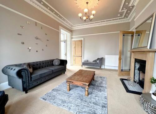 a living room with a black couch and a fireplace at Carlibar Villa in Barrhead