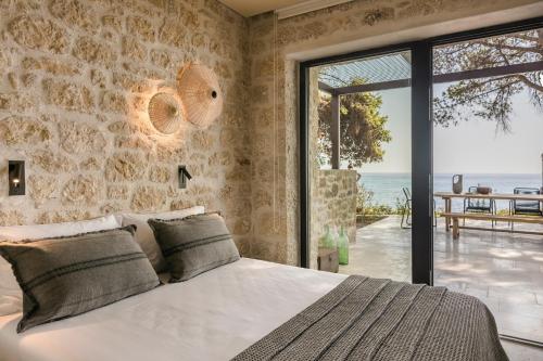 a bedroom with a bed and a stone wall at Home By The Sea in Kardamili
