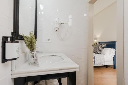a white bathroom with a sink and a bed at nüa cicerone in Seville
