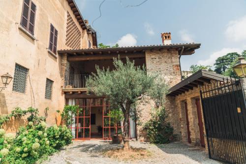 uma velha casa de pedra com uma árvore em frente em Franciacorta Country Lodges em Cazzago San Martino