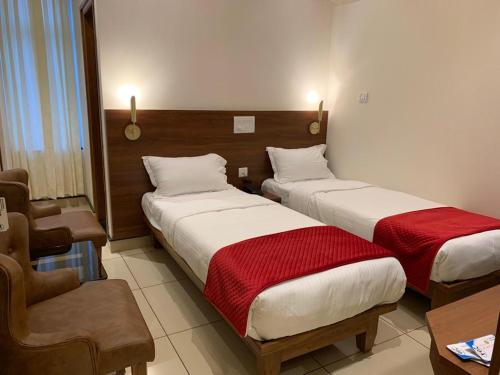una habitación de hotel con 2 camas y una silla en JESTA RESIDENCY, en Hassan