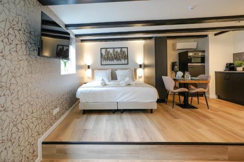 a bedroom with a bed and a table and a kitchen at Luxury City Center Studio in Delft