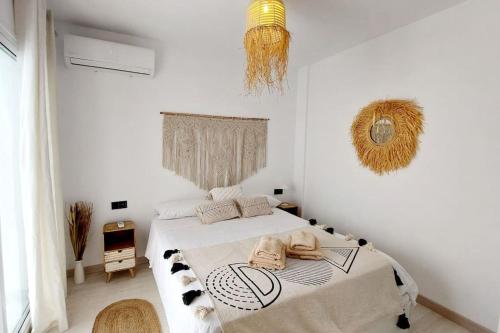 Habitación blanca con cama y lámpara de araña. en Boho Studio with Patio in Centre and Close to Beach, en Nerja