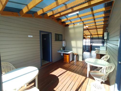 un porche con 2 mesas y sillas en un suelo de madera en T's Resort & Motel, en Port Macquarie