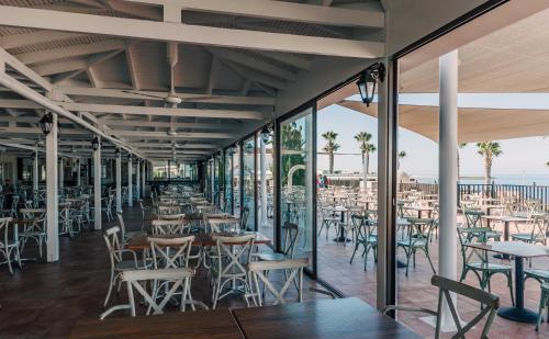 a restaurant with tables and chairs and the ocean at Atlantica Akteon in Paphos