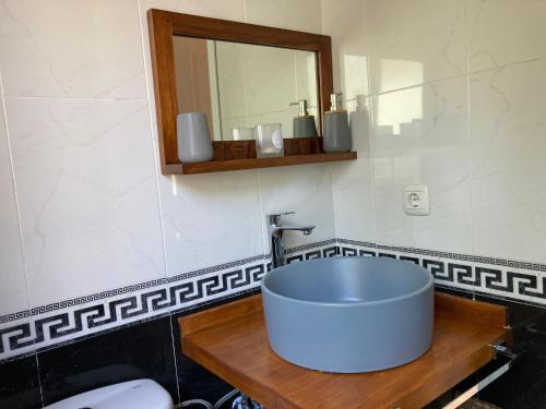 La salle de bains est pourvue d'un lavabo bleu et d'un miroir. dans l'établissement Acogedora casa en Rinlo, en la villa de Ribadeo, à Ribadeo
