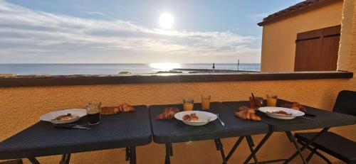 una mesa con comida en el balcón con vistas al océano en T2 avec une vue panoramique sur la mer, en Saint Pierre La Mer