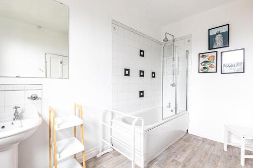baño blanco con ducha y lavamanos en Rovers' Retreat Whitby George Street, en Whitby