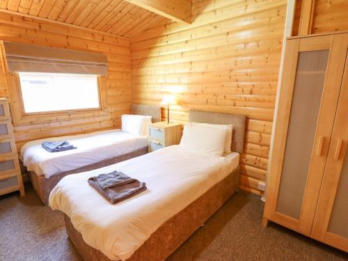 une chambre avec deux lits dans une cabane en rondins dans l'établissement 64 Acorn Lodge Kenwick Park, à Louth